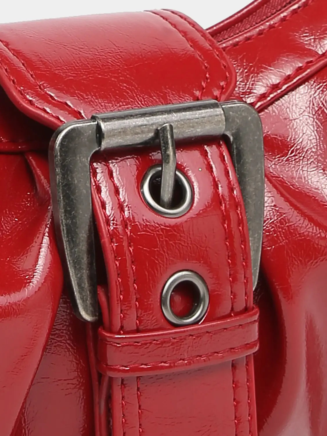 Vintage leather shoulder bag featuring a red patent leather belt buckle with silver-toned metal hardware.