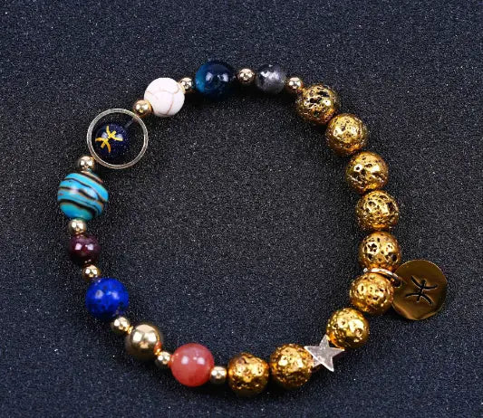 A colorful zodiac volcanic stone beaded bracelet featuring gold-toned textured spheres and vibrant blue red white and purple gemstones with gold charms.