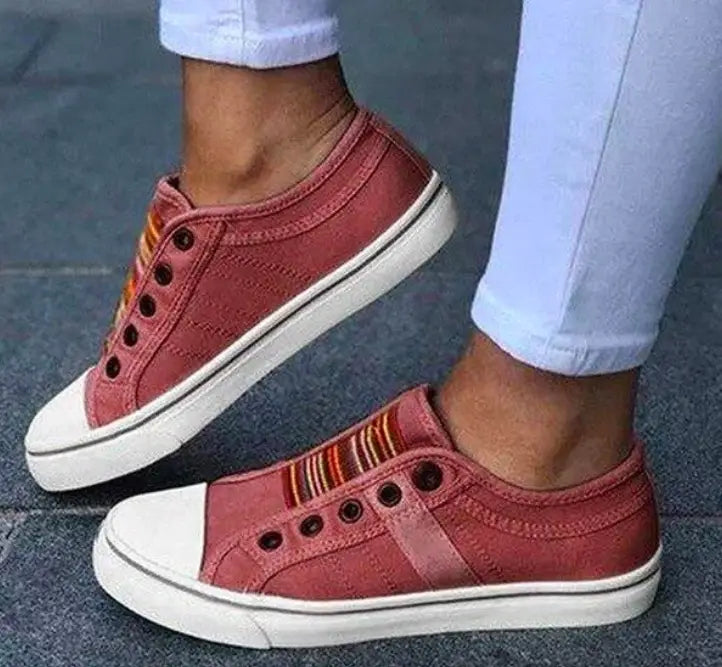 Rosa schnürlose Canvas-Sneaker mit weißen Gummisohlen und einem farbigen gestreiften Akzent an der Seite, gestaltet als Loafer zum Hineinschlüpfen
