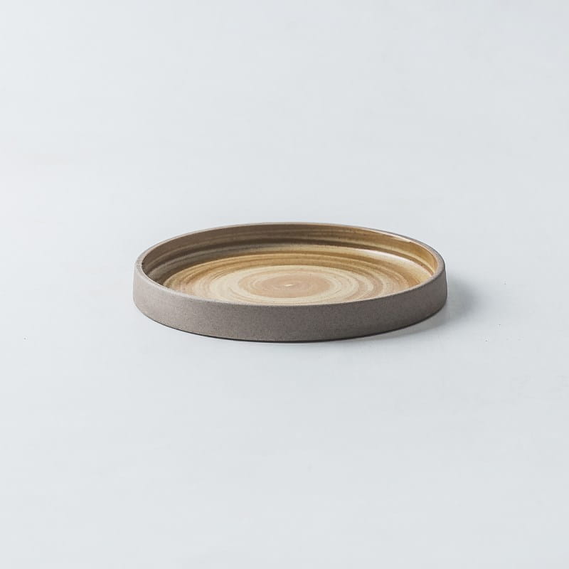 A minimalist ceramic tray with a smooth concentric circular pattern in warm beige and tan tones from a ceramic tableware set retro Japanese dinnerware.