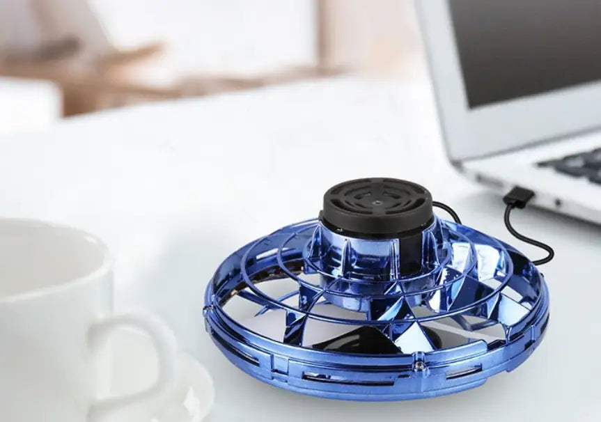 Blue transparent hovering fan with black central motor and charging cable of the flying ufo spinner led mini drone fingertip gyro toy.
