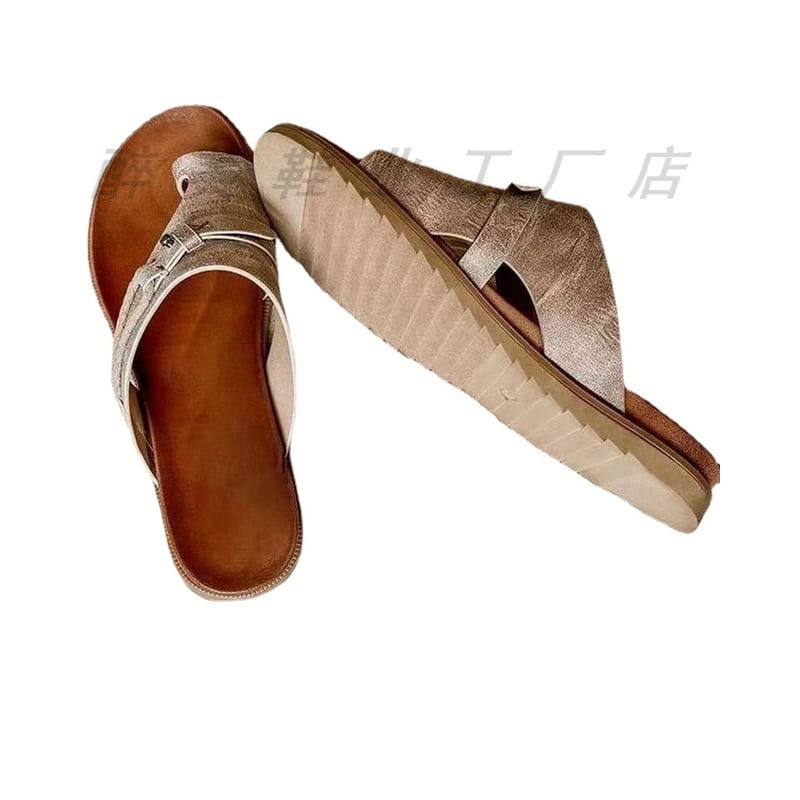 A pair of metallic gold leather women leather thong sandals with a brown insole and textured sole for casual flat platform slides.