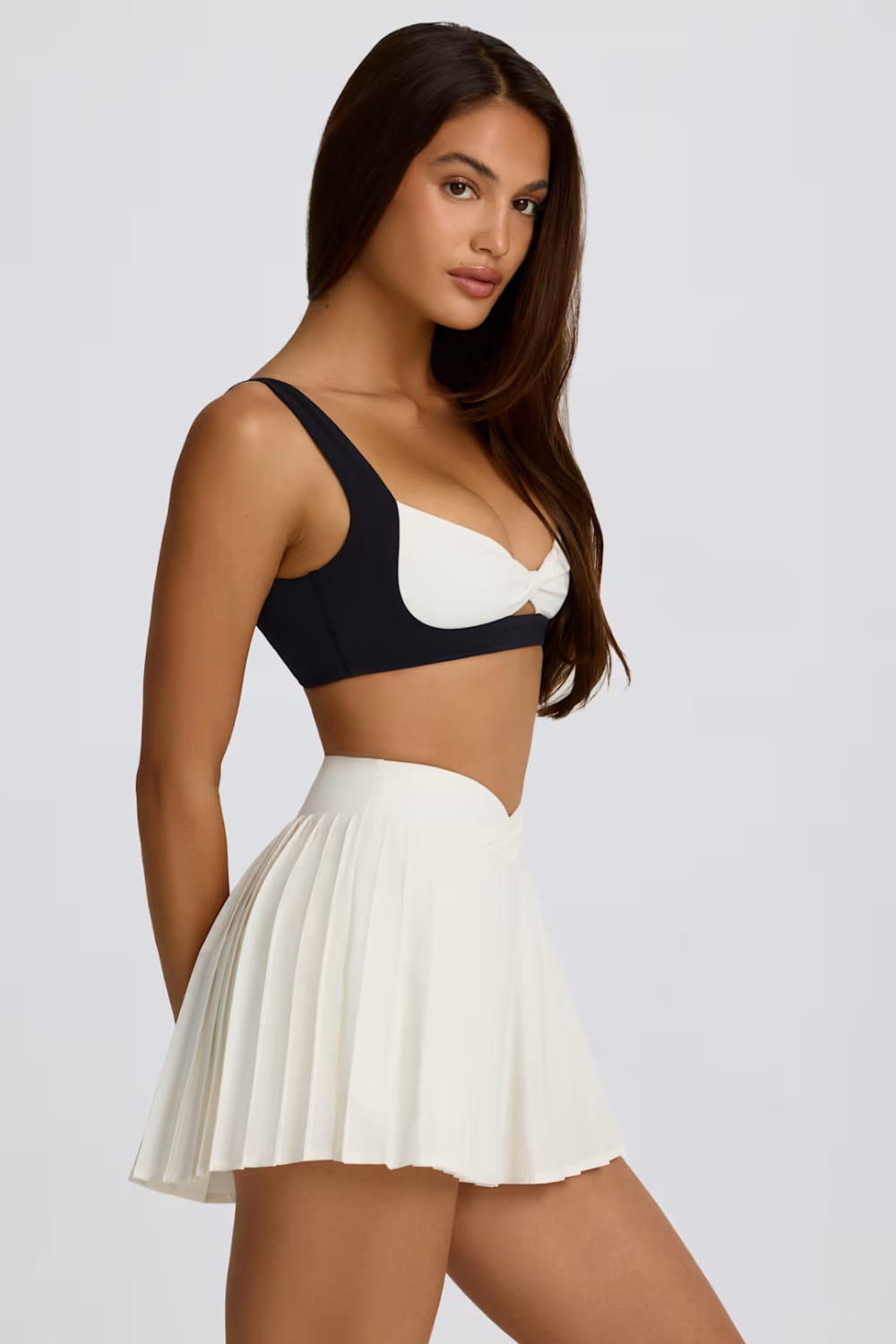 Zweifarbiger Sport-BH in Schwarz und Weiß mit Cut-out-Design, kombiniert mit einem plissierten Sportrock-Skort, der die Figur optisch schlankt.