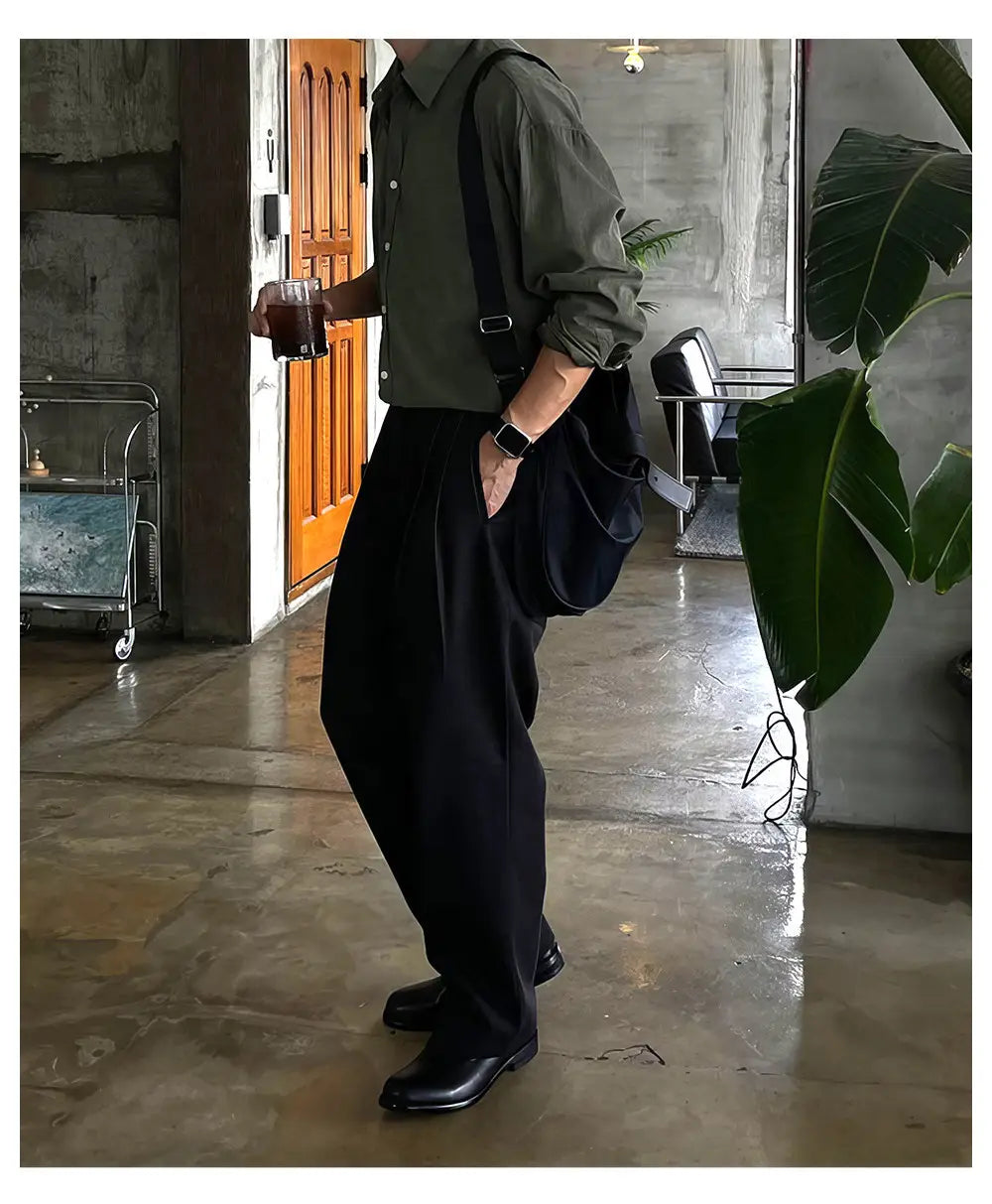 Pantalones tipo sarga de pierna ancha negros para hombre con un diseño minimalista relajado, adecuado para uso formal y casual.