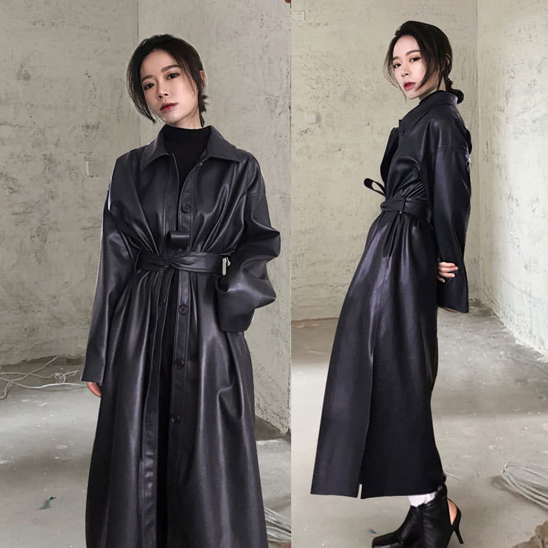Black faux leather trench coat with belted waist and button front designed as a long windbreaker jacket.