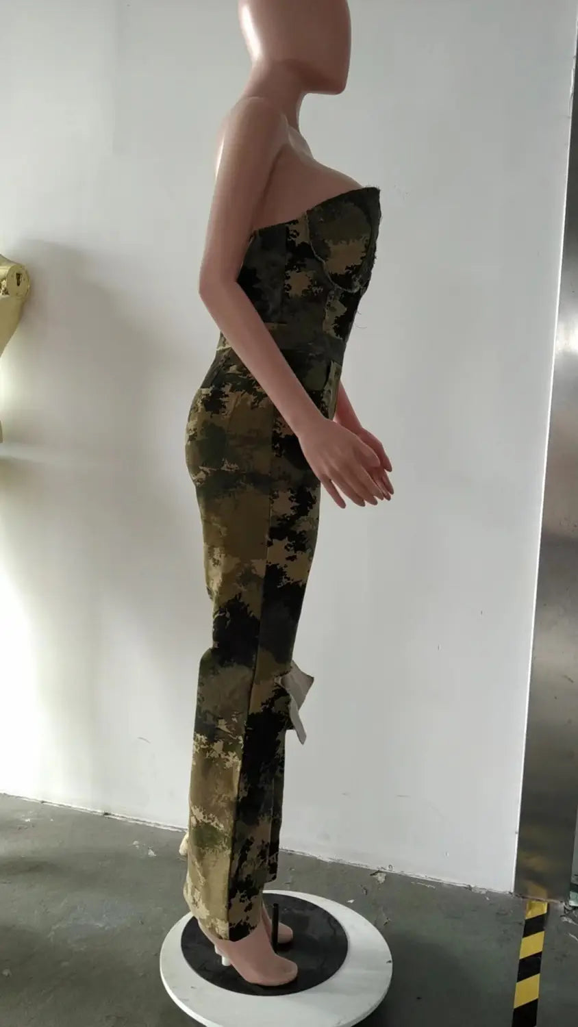 Ein figurbetonter, trägerloser Jumpsuit in Grün- und Braun-Camouflage-Optik mit gerafften Details entlang der Seiten und ausgestellt geschnittenen Jeansbeinen.