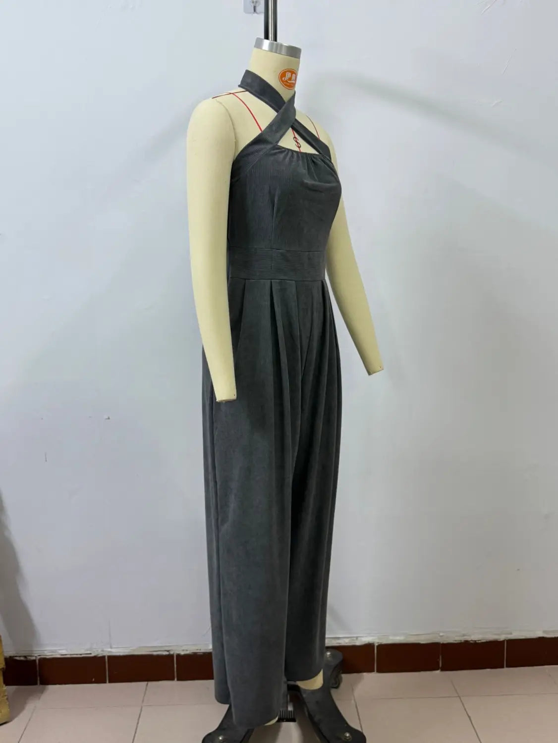 Dunkelgrauer Samt-Halterneck-Jumpsuit mit weitem Bein, mit gekreuzten Schulterträgern und einer plissierten Taillen-Detailierung.