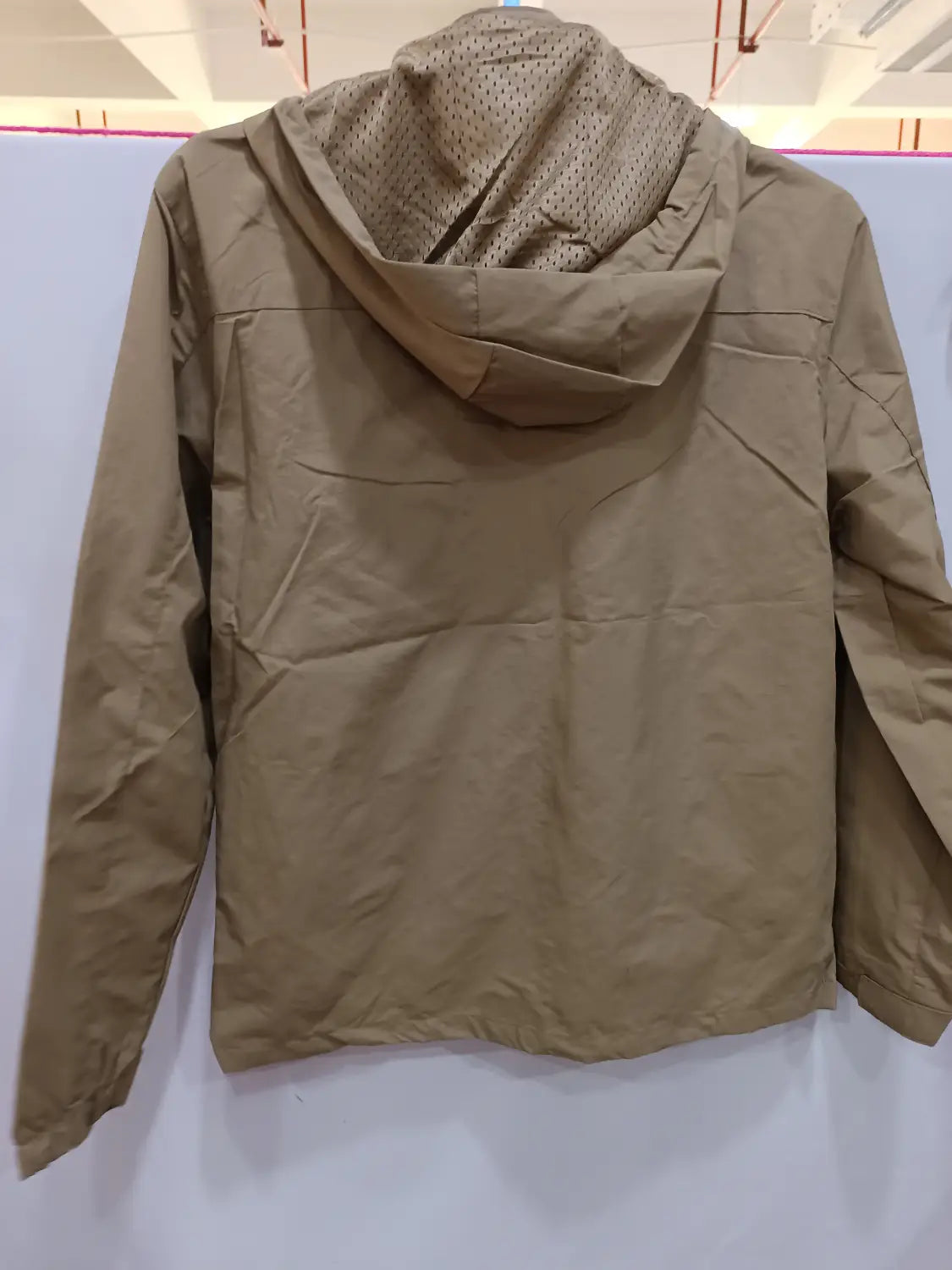 Chaqueta de senderismo con capucha impermeable color camel, con un forro de malla interior perforado en la capucha para mejorar la transpirabilidad.