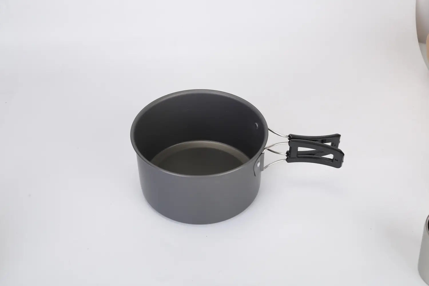 Olla de aluminio para camping gris con revestimiento antiadherente, asa de plástico negro y remaches metálicos, del set de utensilios de camping de 12 piezas.