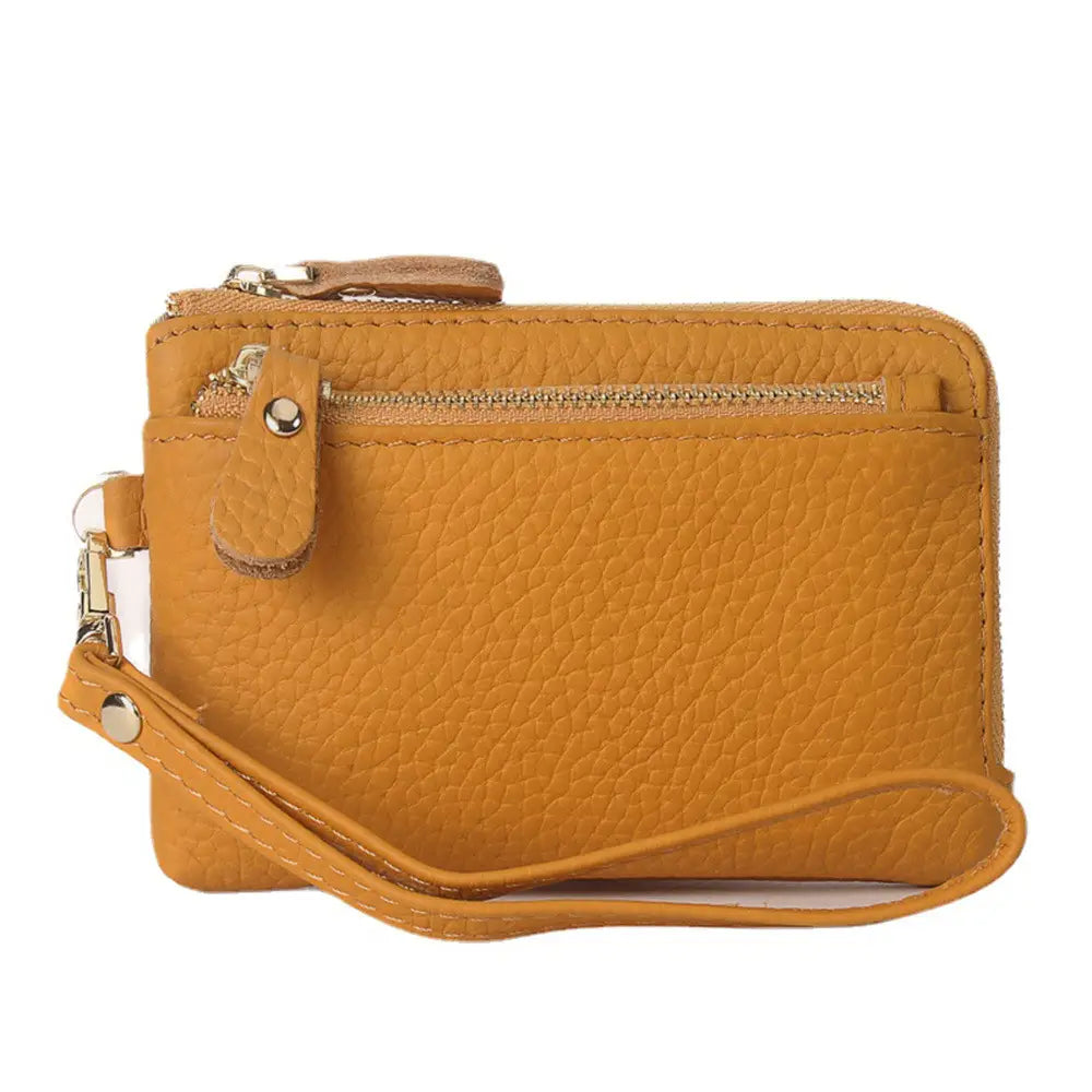 A mustard-yellow premium textured leather wristlet wallet with gold metallic hardware features a zippered top and a detachable strap.