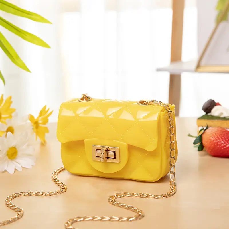 Bright yellow glossy resin mini quilted pearl crossbody bag for women with gold tone chain strap and clasp.