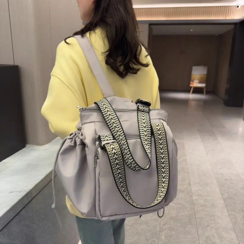 Multifunctional waterproof nylon fashion tote and backpack in gray with black and white geometric-patterned straps.