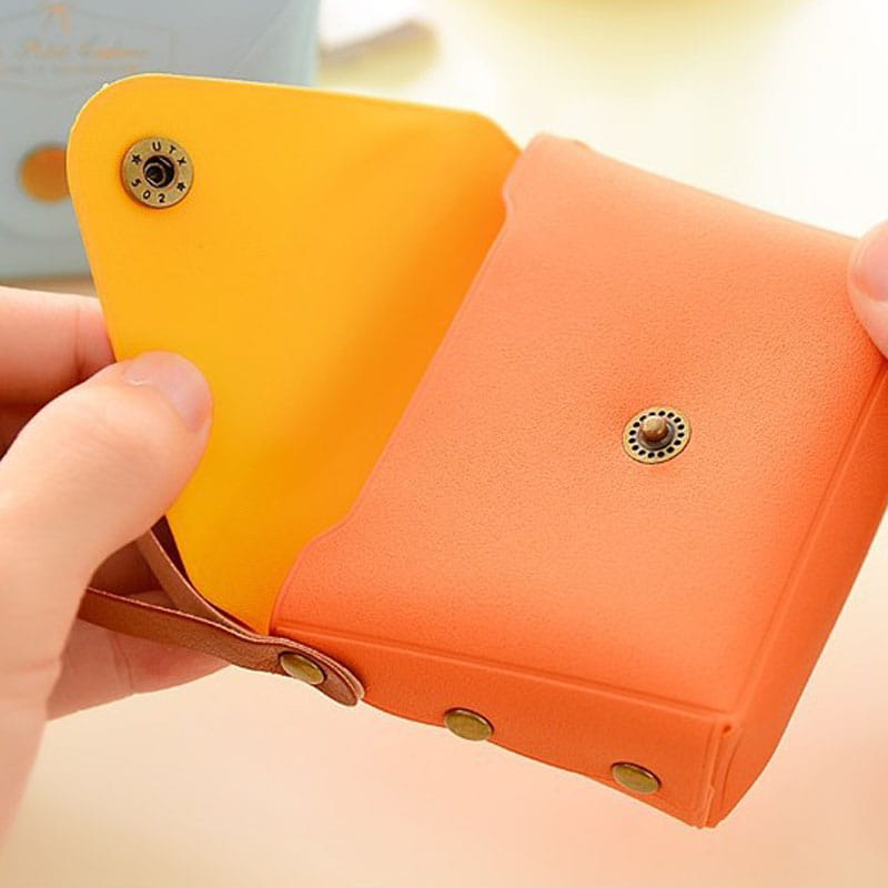 A vibrant two-tone Macaron Pastel leather and PVC coin purse set with a mustard yellow interior, orange exterior, brass-toned snap buttons, and brown leather straps.
