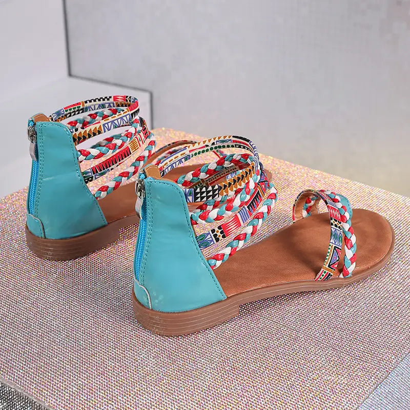 Bohemian ethnic braided ankle strap flat sandals featuring turquoise and brown woven straps with colorful geometric patterns.