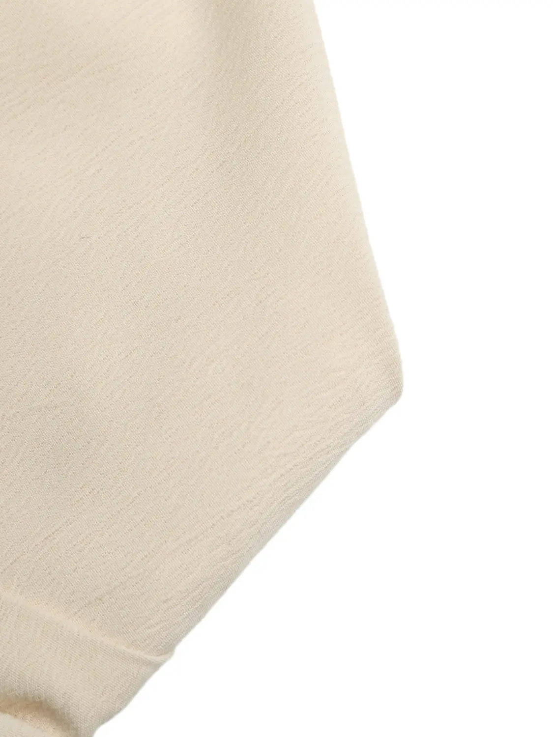 Cream-colored canvas tote bag with a soft textured fabric finish paired with a cream strapless pleated jumpsuit.