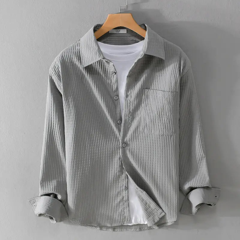 Chemise homme décontractée à manches longues en velours côtelé gris, avec une texture côtelée subtile et une poche poitrine unique.