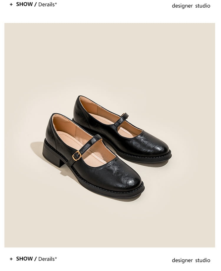 Black leather mary jane shoes with a low block heel and gold toned buckle shown from the back.