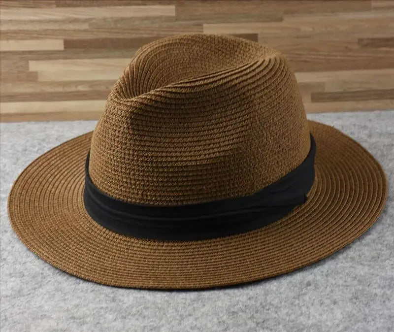 Brown woven straw fedora hat with a black ribbon band featuring a foldable design for sun protection for men.