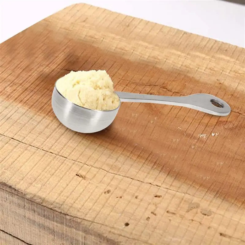A shiny 304 stainless steel measuring cup filled with a pale yellow creamy substance for precise kitchen measurements.
