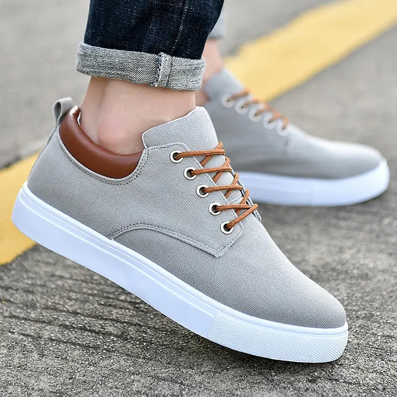 Men’s breathable casual sport canvas sneakers in gray with brown laces and a white rubber sole.