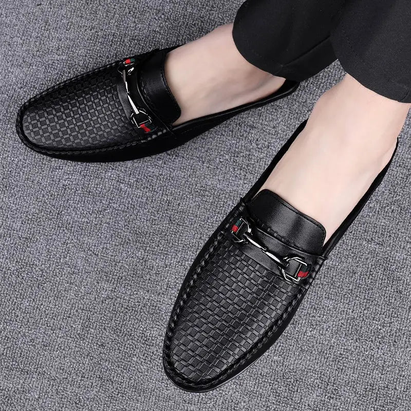 Men’s black leather mule loafers with woven texture and silver-toned horsebit buckle accented by red stitching.