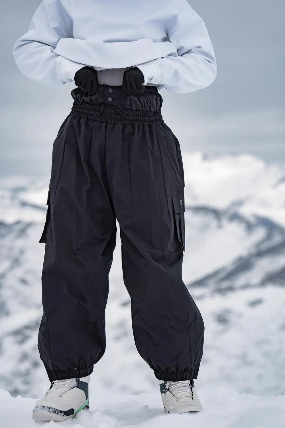 Black high-waisted winter outdoor loose ski pants with elastic cuffs and multiple cargo pockets designed for cold weather activities.