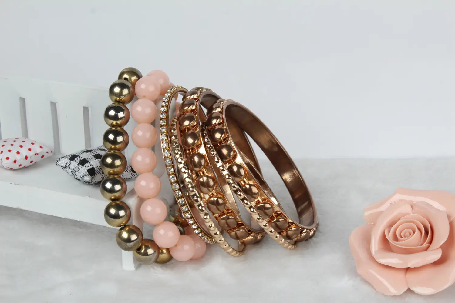 A set of rose gold and pink beaded retro gold and pink rhinestone bangle bracelets with metallic accents.