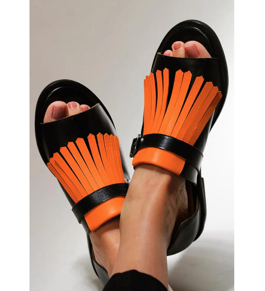 Women’s tassel leather beach sandals in black and cream with black and orange fringe and a sleek modern design.