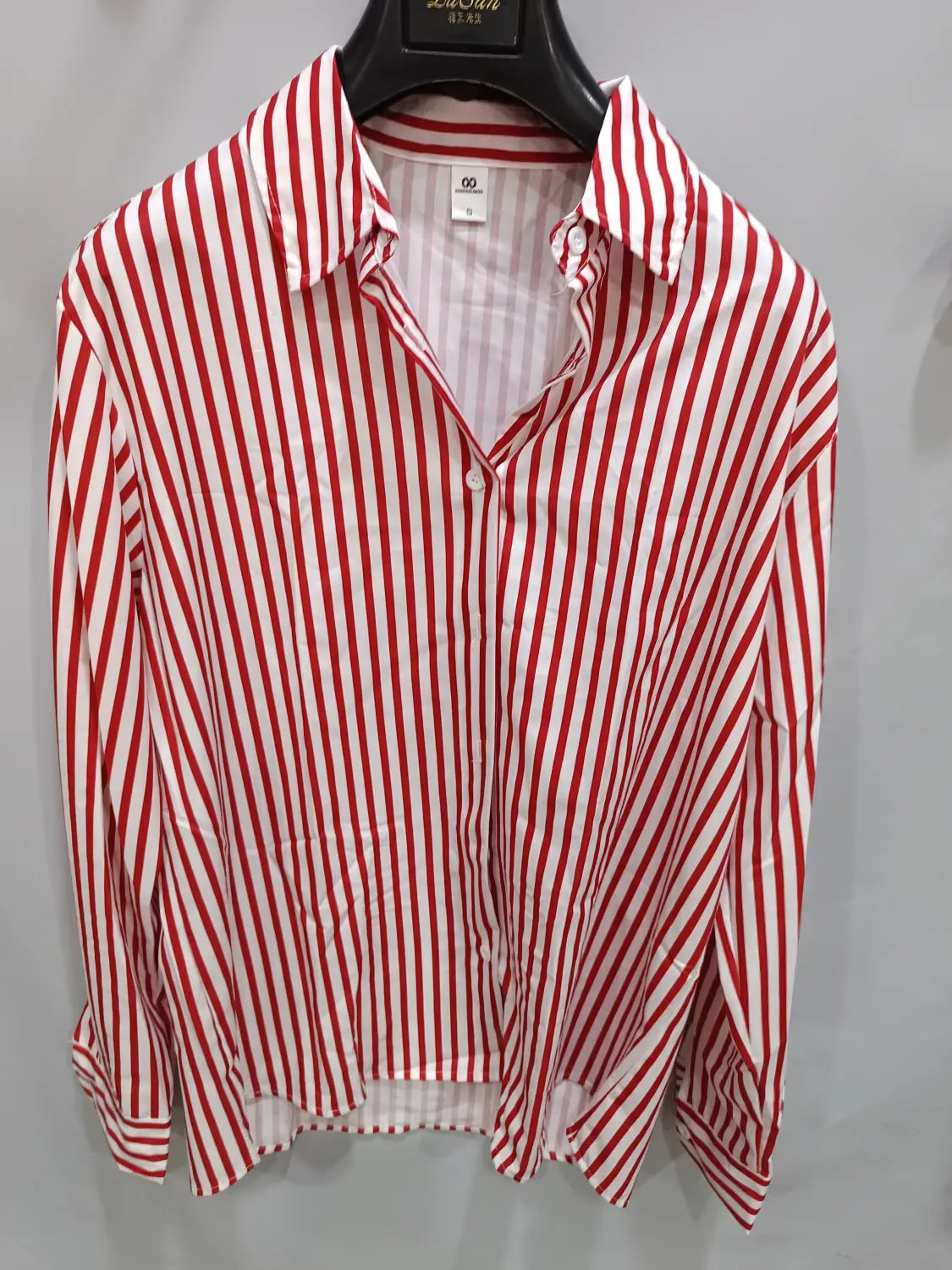 Chemise décontractée à manches longues rayée verticalement rouge et blanc pour hommes, à patte boutonnée et col, suspendue sur un cintre noir