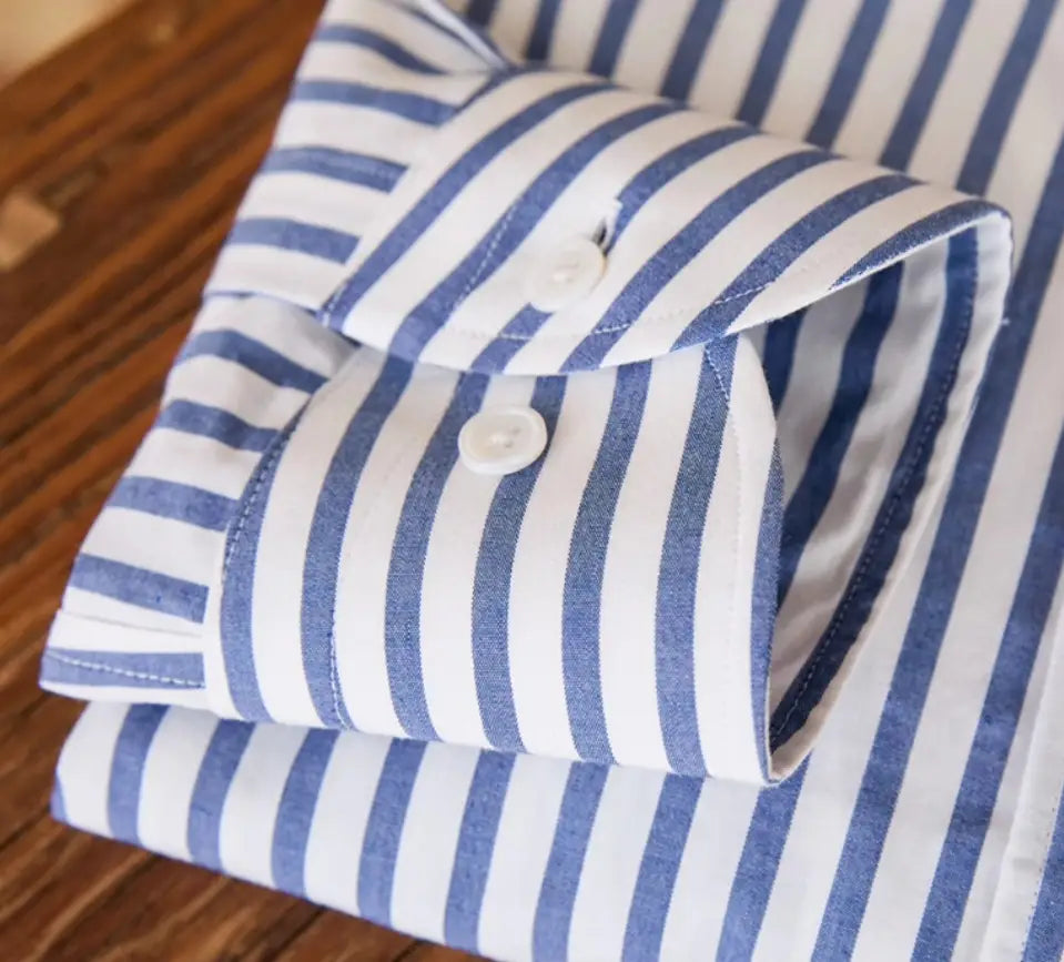 Ein ordentlich gefaltetes Slim-Fit gestreiftes Baumwoll-Hemd langarm für den Pendlerbereich in Blau und Weiß mit fester Stoffqualität und klassischem Kragen.