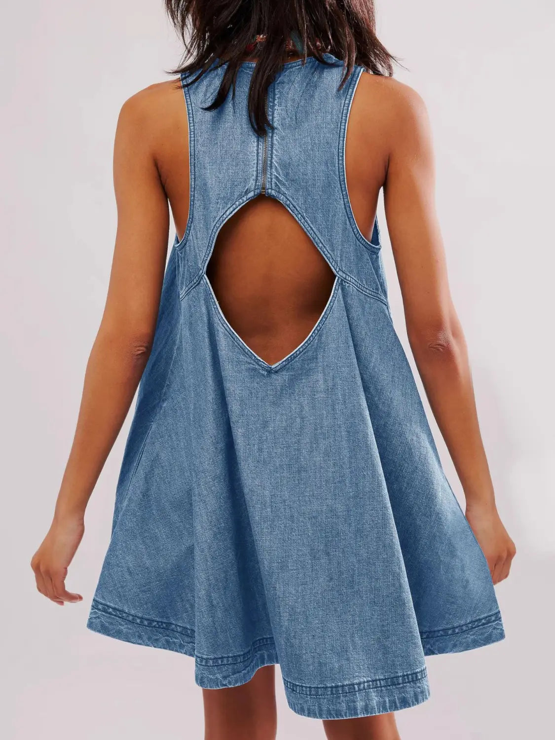 Ein hellblaues Jeans-Minikleid, von der Rückseite gezeigt, mit einem markanten Design für ein hinten offenes Schleifen-Detail.