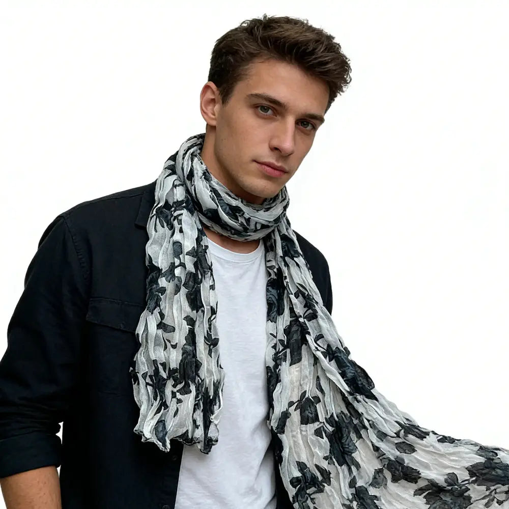 Un foulard en mousseline de crêpe (chiffon) froissé noir et blanc à motif floral, porté autour du cou, mettant en valeur sa texture fluide.