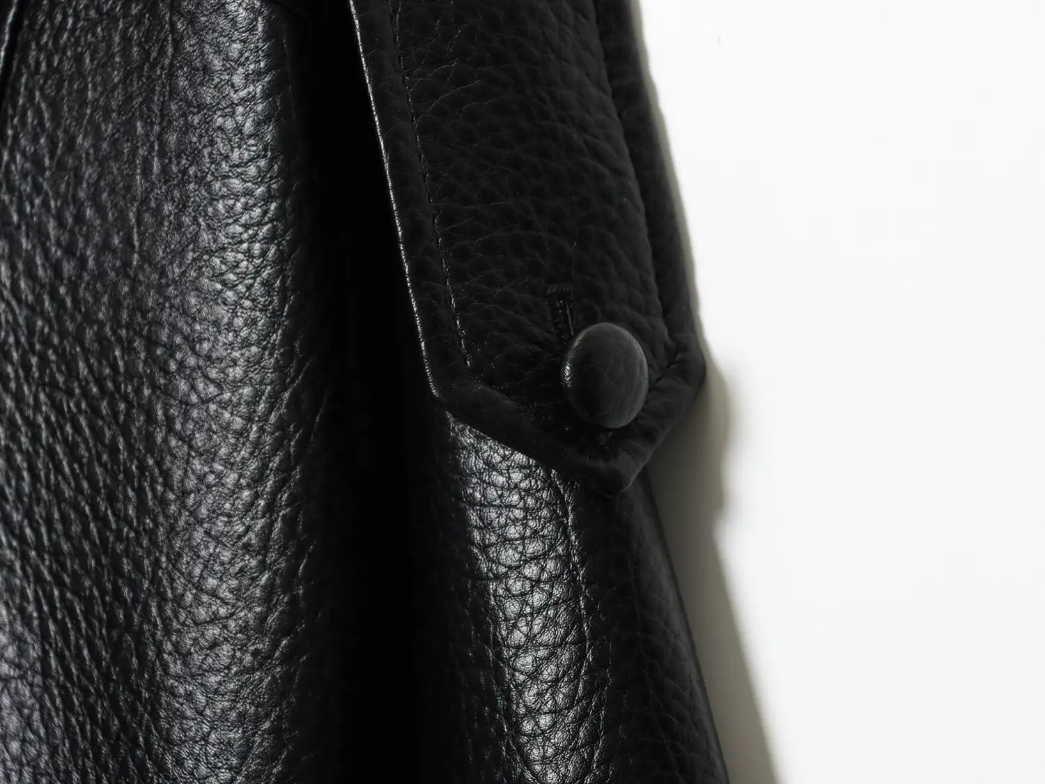 Schwarze Damen-Motorradjacke mit hohem Stehkragen aus Kunstleder mit schwarzem strukturiertem Leder und einer mattschwarzen Knopfverzierung.