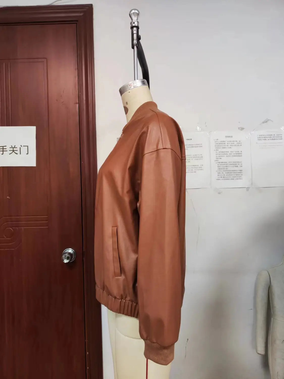 A sleek tan faux leather bomber jacket with ribbed cuffs and hem.