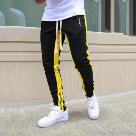 Men’s black athletic joggers with bold yellow side stripes white drawstring and zipper cuffs designed for activewear.