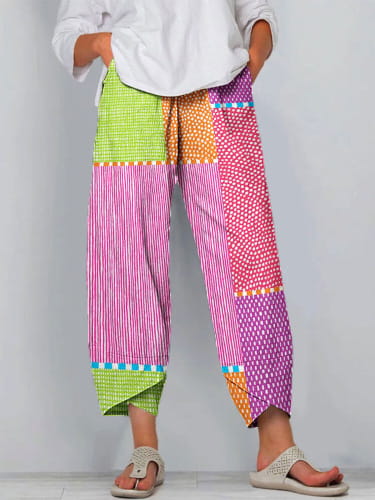 Artistic printed and embroidered slimming cropped pants in a brightly colored patchwork design featuring lime green, pink, purple, and orange panels with striped and dotted patterns.