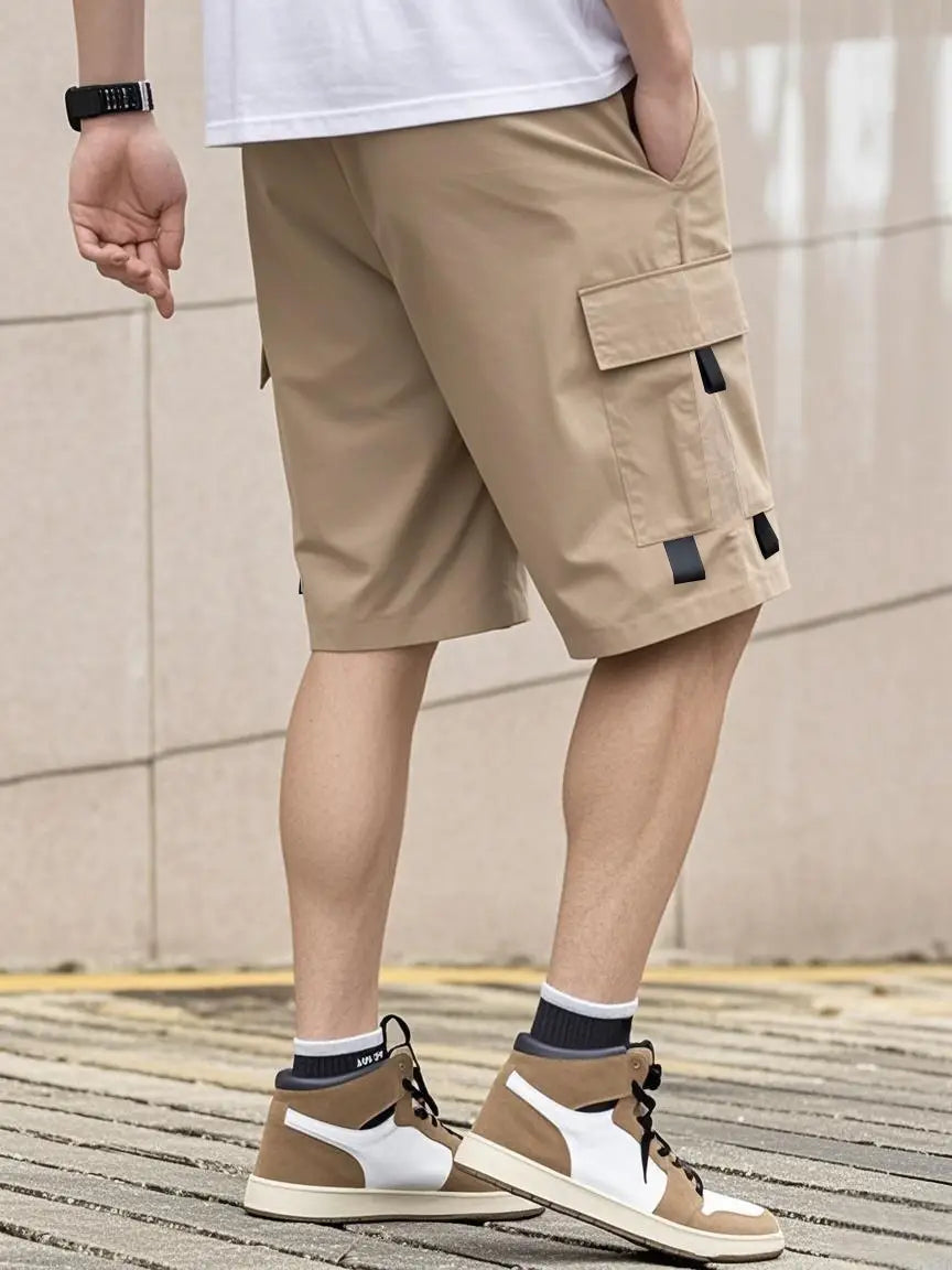 Shorts cargo utilitaires pour homme beige, avec des accents en tissu noir sur les poches, présentant un design décontracté à cordon de serrage pour une tenue d’été.