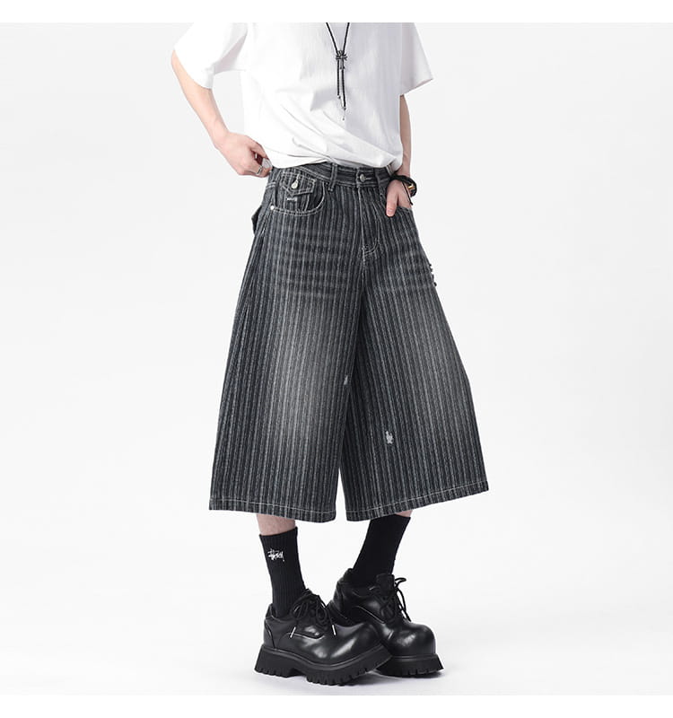 Striped denim capri shorts featuring black and white vertically striped wide-leg design with distressed faded finish.