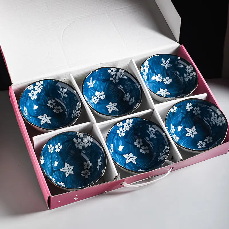 Six blue ceramic bowls with white floral patterns and gold rims neatly arranged in a pink gift box in a porcelain 5 inch ceramic bowl set.