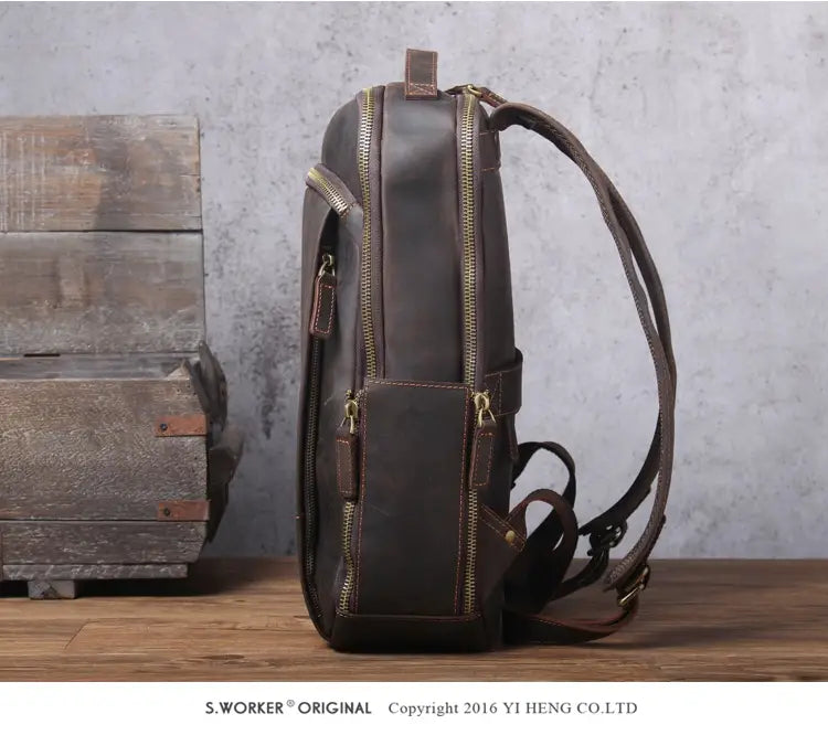 Men’s vintage leather backpack in dark brown cowhide featuring brass zippers and matching straps.