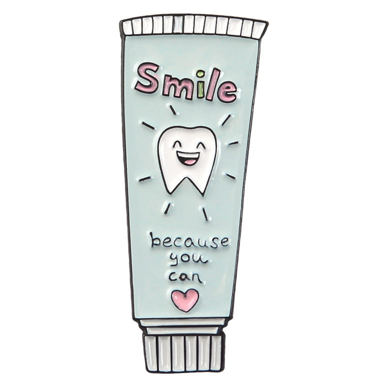 A mint green enamel pin shaped like a toothpaste tube with the word smile in pink and black lettering featuring a smiling cartoon tooth and the phrase because you can titled toothpaste smile enamel pin cartoon tooth brooch.