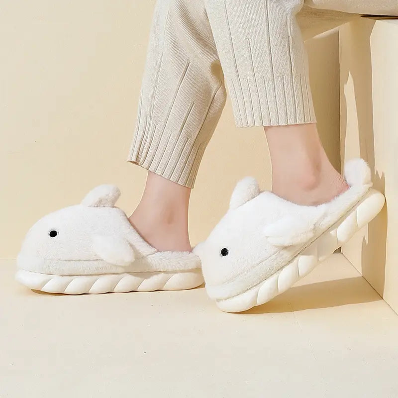white plush whale shaped shark slippers with black eye details and textured ribbed sole for indoor use