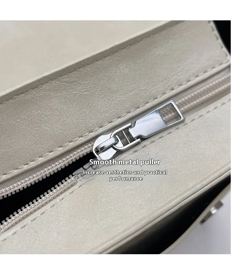 Silberfarbener Metall-Zipper-Anhänger mit glatter, eleganter Oberfläche an einer Schleifen-Umhängetasche aus Kunstleder als modische Handtasche.