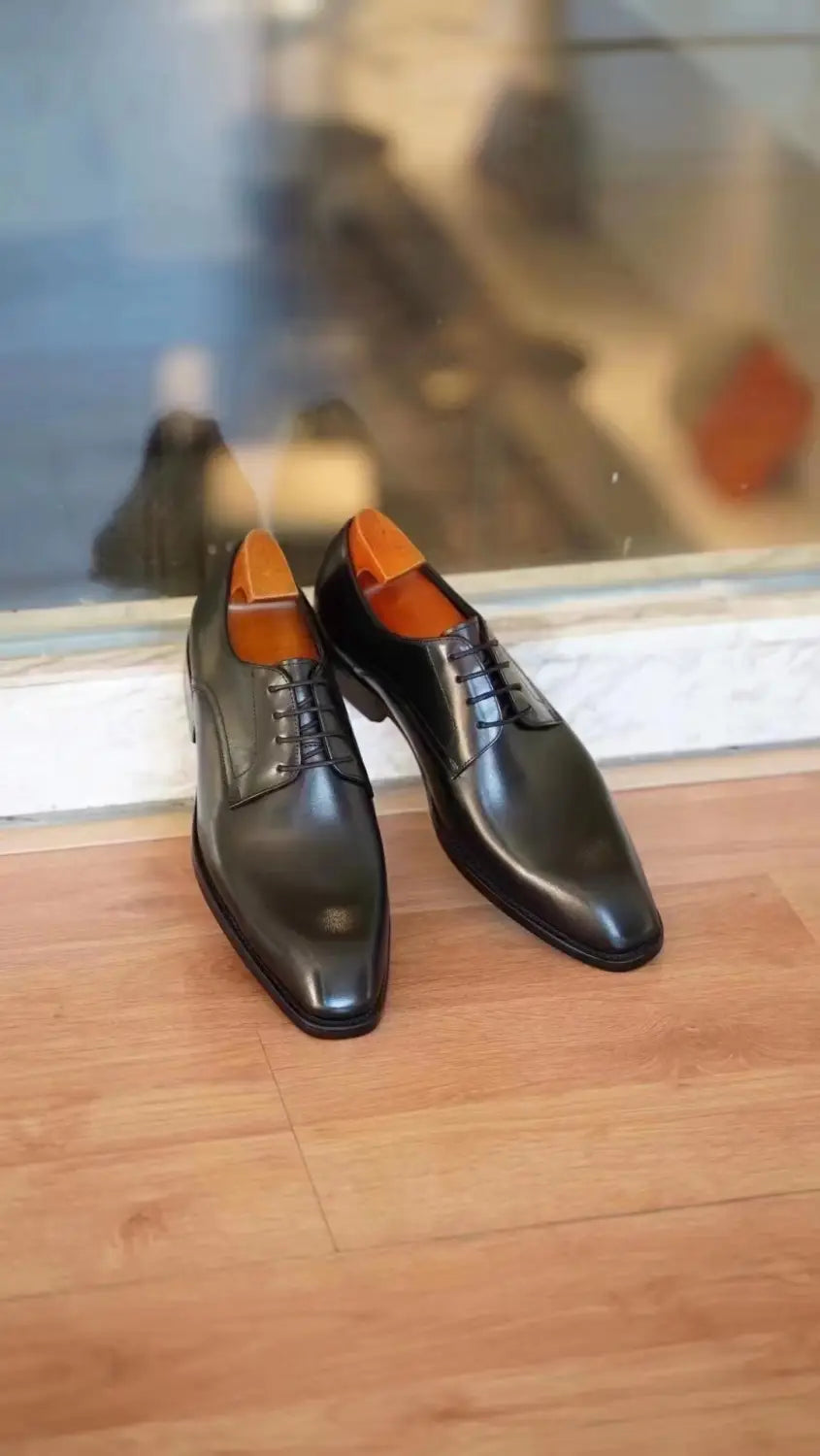 Herren-Oxfordschuhe mit eckiger Kappe aus beschichtet wirkendem Leder in Schwarz, mit orangenen Einlegesohlen.