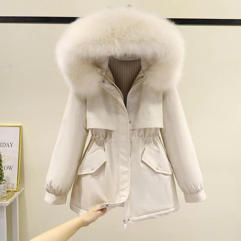 Damen Winter-Pufferjacke in mittlerer Länge in cremefarben mit einer plüschigen weißen Fellverbrämung an der Kapuze und zwei vorderen Taschen, ausgelegt für die Winterbekleidung.