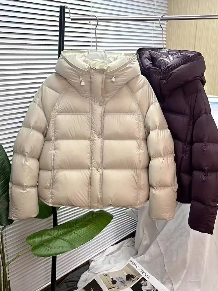Cream-colored quilted down puffer jacket with a hood and button closure designed as a loose hooded winter coat.