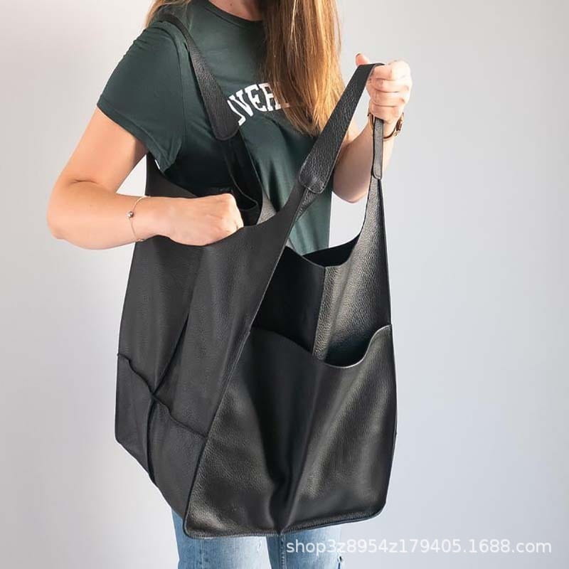 Black leather tote bag with a textured surface and multiple interior pockets offering large capacity and soft slouchy shoulder design.