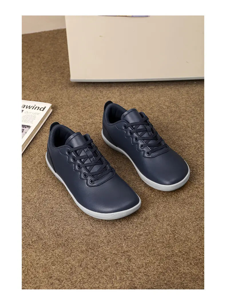 Dunkelblaue Leder-Sneaker im Low-Top-Format mit weißen Gummisohlen, entworfen als minimalistische Freizeitschuhe für den Outdoor-Einsatz.