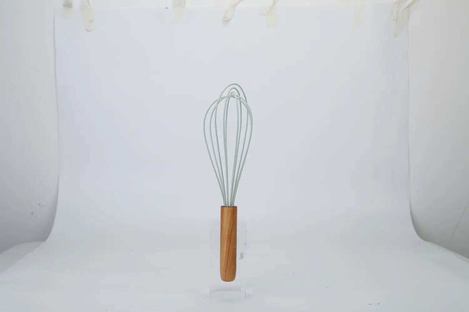 A sleek light gray wire whisk with a smooth wooden handle from the silicone cooking utensil set 11pc with wood handles.