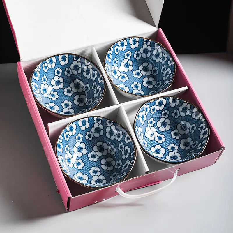 Set of four blue and white floral ceramic bowls with gold rims and a 5 inch diameter neatly arranged in a pink gift box.
